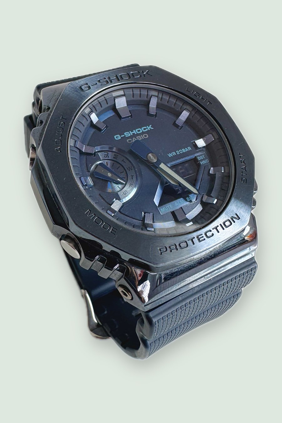 The same G-Shock watch on a soft sage green background in a 2:3 portrait aspect ratio